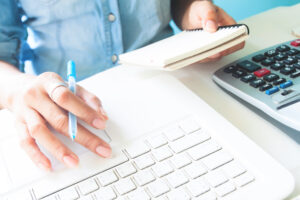 Business woman using laptop computer and calculator